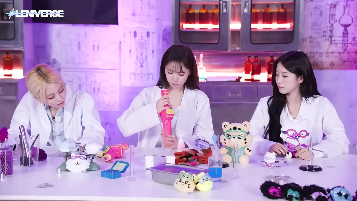 Las integrantes de LE SSERAFIM posan con herramientas de juguete en el set del laboratorio de LENIVERSE